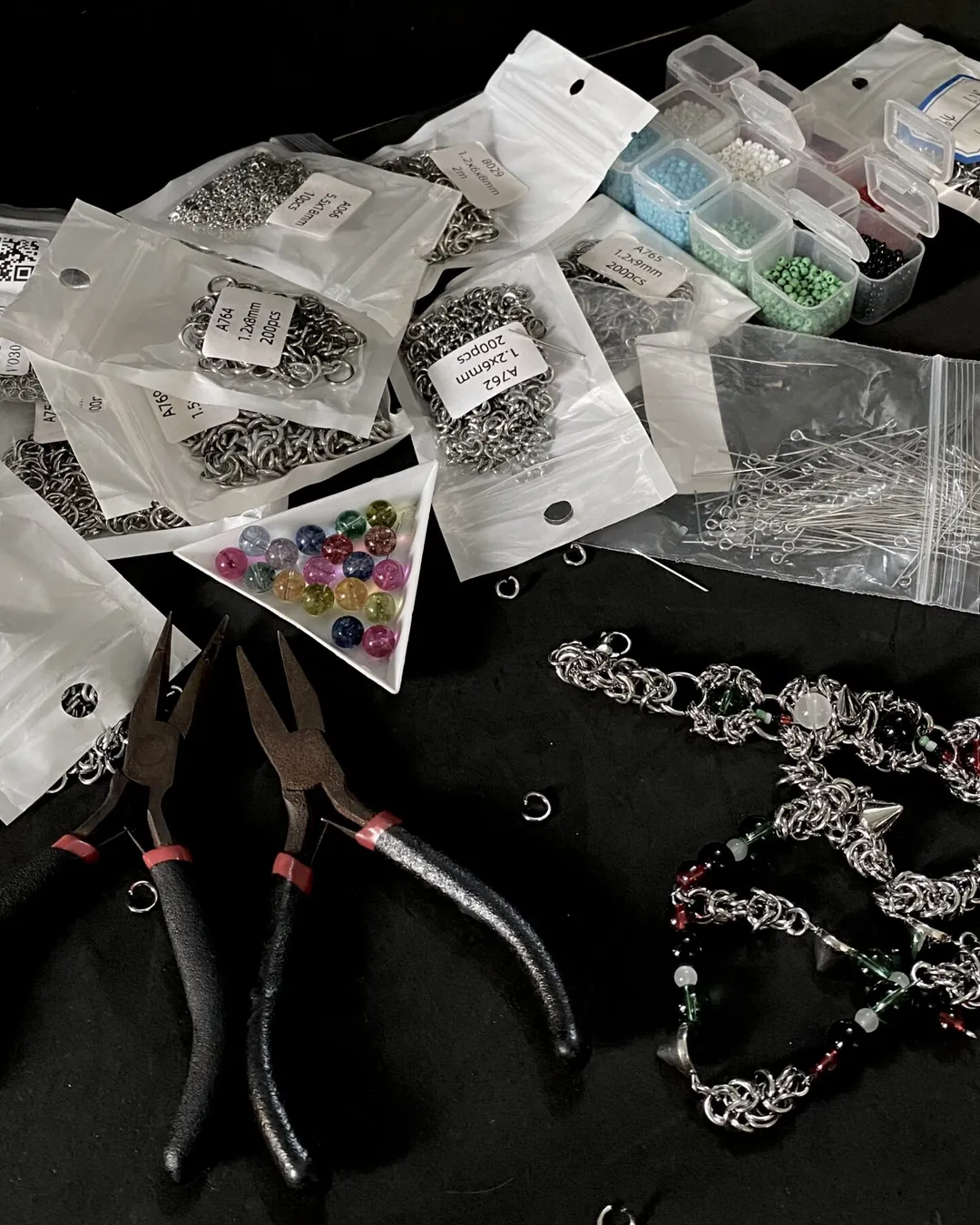 The Grizz Studio® workbench: pliers, bags of steel jump rings, glass beads and a chainmail piece in progress